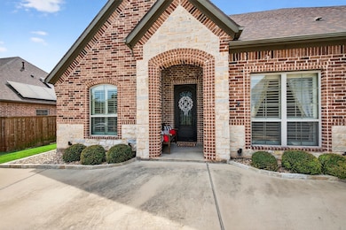 Doorway to property with brick siding, stone siding, and a shingled roof