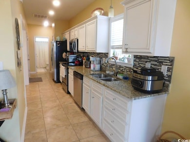 Kitchen with a sink, stainless steel appliances, decorative backsplash, and white cabinetry