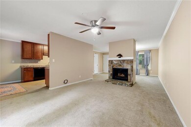 Unfurnished living room with crown molding, light carpet, ceiling fan, and a stone fireplace