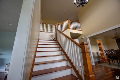 Stairway with a chandelier, wood finished floors, and a high ceiling
