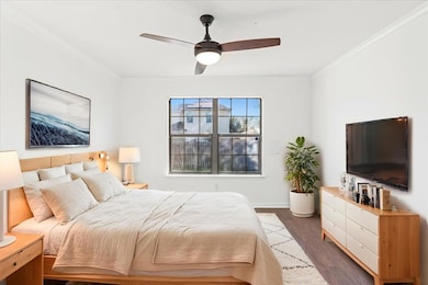Bedroom with dark wood finished floors, a ceiling fan, and ornamental molding