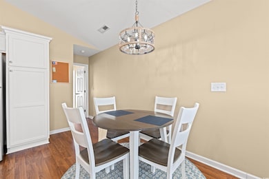 Dining room featuring dark wood-style flooring, lofted ceiling, and a chandelier
