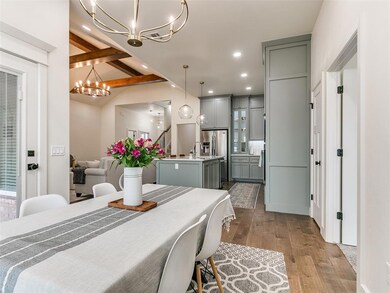 Dining area with light hardwood / wood-style flooring, sink, a notable chandelier, and beamed ceiling