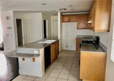 Kitchen featuring a sink, brown cabinets, light ti