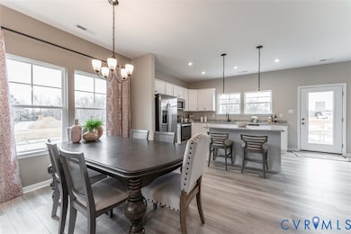 Dining space with light wood-type flooring, a chandelier, and recessed lighting