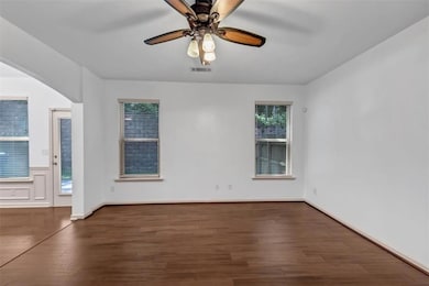 Spare room with wood finished floors, ceiling fan, and arched walkways