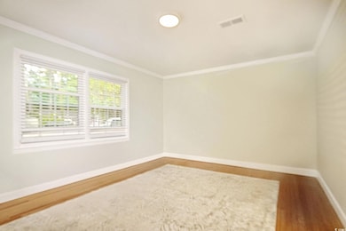 Empty room featuring ornamental molding, baseboards, and wood finished floors