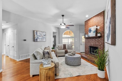 Living room featuring a brick fireplace, ceiling fan, wood finished floors, and recessed lighting