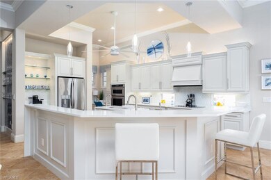 Kitchen with ornamental molding, stainless steel appliances, backsplash, light tile patterned floors, and white cabinetry
