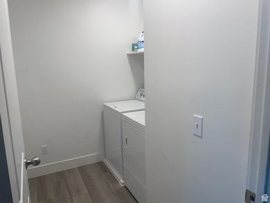 Laundry area with dark wood-type flooring and washing machine and clothes dryer