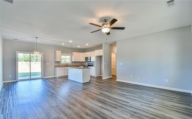 Kitchen featuring stainless steel appliances, open floor plan, baseboards, a sink, and ceiling fan