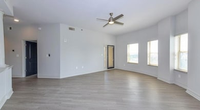 Unfurnished room featuring ceiling fan, hardwood / wood-style flooring, and ornate columns