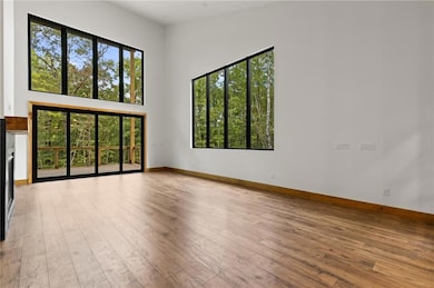 Spare room with plenty of natural light, a towering ceiling, light wood-type flooring, and a fireplace