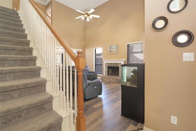 Staircase with a brick fireplace, ceiling fan, dar