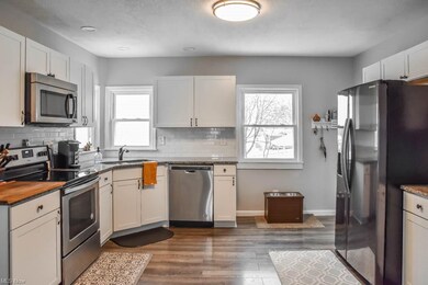 Updated kitchen with white cabinetry, granite coun