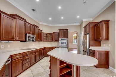 Kitchen featuring open shelves, arched walkways, ornamental molding, light tile patterned floors, and a center island