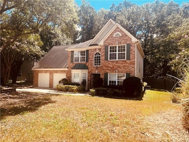 View of front of house featuring brick siding, an attached garage, and view of wooded area