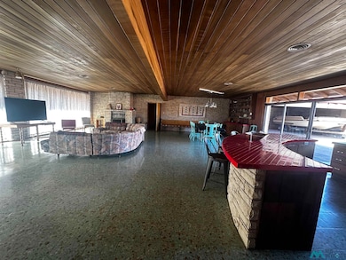 Living room with brick wall, wood ceiling, and a fireplace