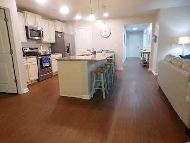 Kitchen featuring appliances with stainless steel finishes, a sink, white cabinets, dark wood finished floors, and recessed lighting