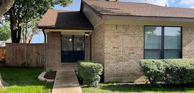 Doorway to property with brick siding and a shingled roof