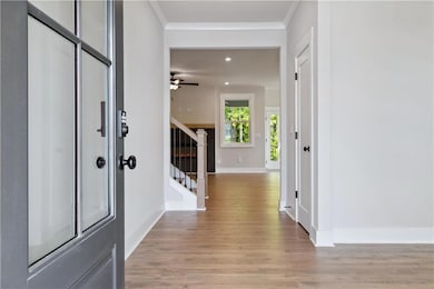 Foyer with crown molding, baseboards, light wood-s