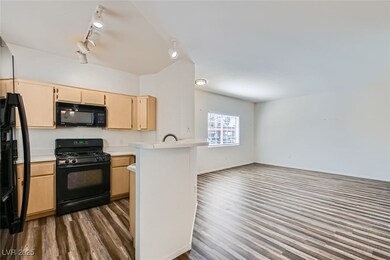 Kitchen featuring black appliances, light brown cabinetry, light countertops, open floor plan, and dark wood-style flooring