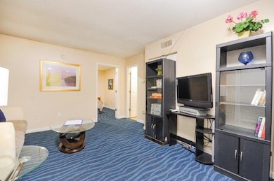 Living area featuring dark carpet and a textured ceiling