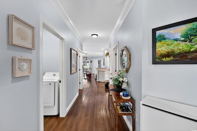 Hall featuring washer / clothes dryer, dark wood-style flooring, and ornamental molding