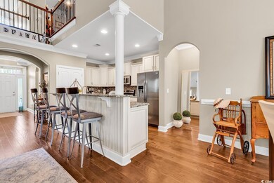 Kitchen with stainless steel appliances, a towering ceiling, arched walkways, light stone countertops, and a kitchen bar
