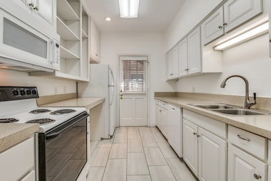Kitchen featuring white appliances, light countertops, open shelves, white cabinetry, and recessed lighting