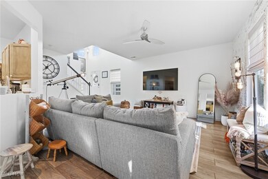 Living room with light wood-style flooring, stairs, and ceiling fan