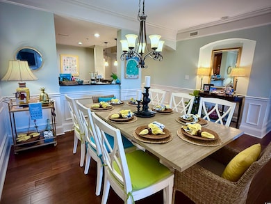 Dining area featuring a decorative wall, wood finished floors, crown molding, wainscoting, and a chandelier