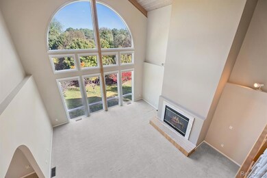 Unfurnished living room with a towering ceiling, carpet floors, and a glass covered fireplace