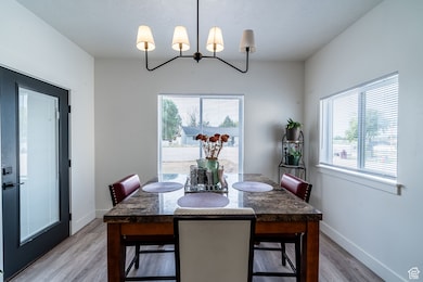 Dining space with a textured ceiling, a chandelier, and light wood-style flooring