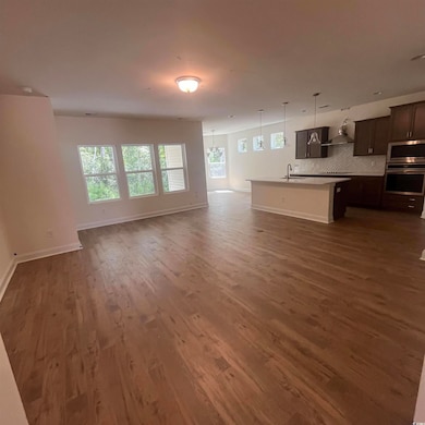 Unfurnished living room featuring dark wood finished floors and baseboards