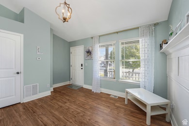 Entryway living room featuring dark wood-type flooring, a chandelier, and lofted ceiling