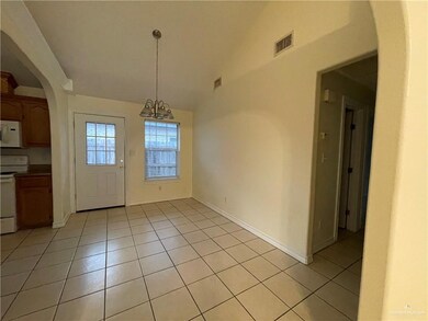 Unfurnished dining area with lofted ceiling, arched walkways, light tile patterned floors, and a chandelier