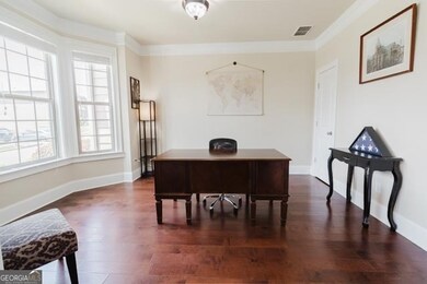 Office area/guest room on main featuring dark wood-type flooring and crown molding