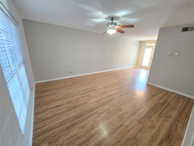 Empty room featuring light wood-style flooring, a chandelier, and ceiling fan