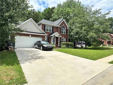Traditional-style home with brick siding, driveway, a front lawn, and an attached garage