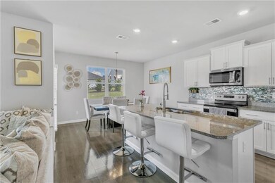 Kitchen featuring appliances with stainless steel finishes, a sink, a breakfast bar, a kitchen island with sink, and stone countertops