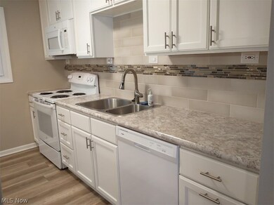 Kitchen with white cabinetry, tasteful backsplash, white appliances, hardwood / wood-style flooring, and sink