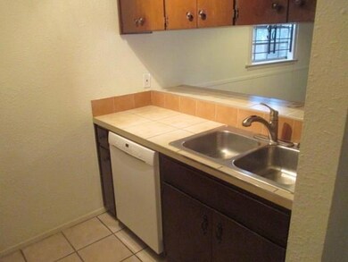 Kitchen with white dishwasher, light tile pattern