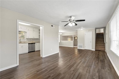 Unfurnished living room featuring dark wood-style flooring, stairs, ceiling fan, and a textured ceiling