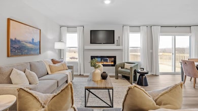 Cozy living room with electric fireplace and an abundance of natural light. Model home, finishes will vary.