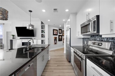Kitchen featuring stainless steel appliances, a sink, light wood finished floors, pendant lighting, and white cabinets