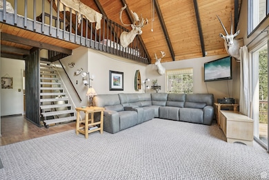 Living room with a wooden ceiling with exposed beams, high vaulted ceiling, stairway, and wood finished floors