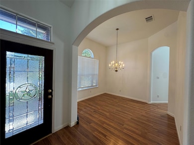 Entryway with dark wood-style flooring, a chandelier, and arched walkways