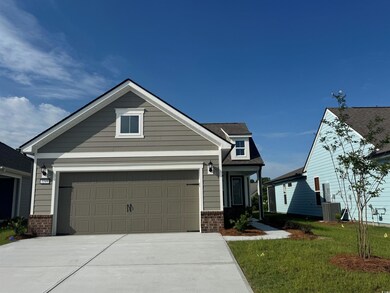 View of front facade featuring brick siding, concrete driveway, a front yard, cooling unit, and a garage