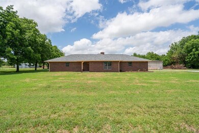 Back of property featuring a lawn, brick siding, and a chimney